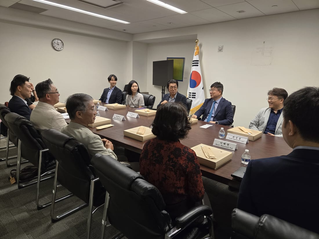 KAMDA leadership in discussion around a conference table at the Consulate General of Korea in New York, with the Korean flag behind them.